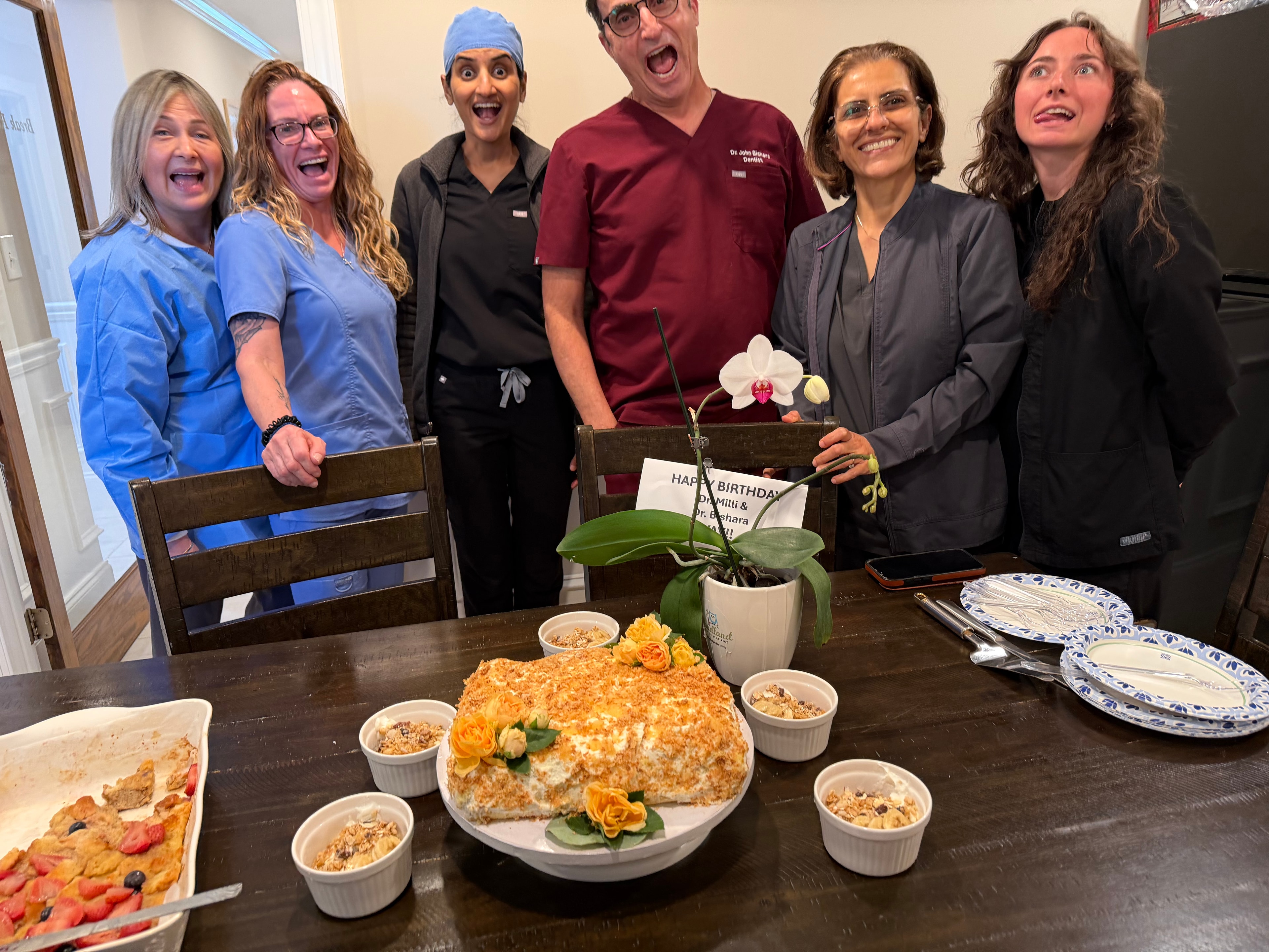 Merchants Walk Dental team making silly faces around a homemade birthday cake for Dr. Bishara and Dr. Patel