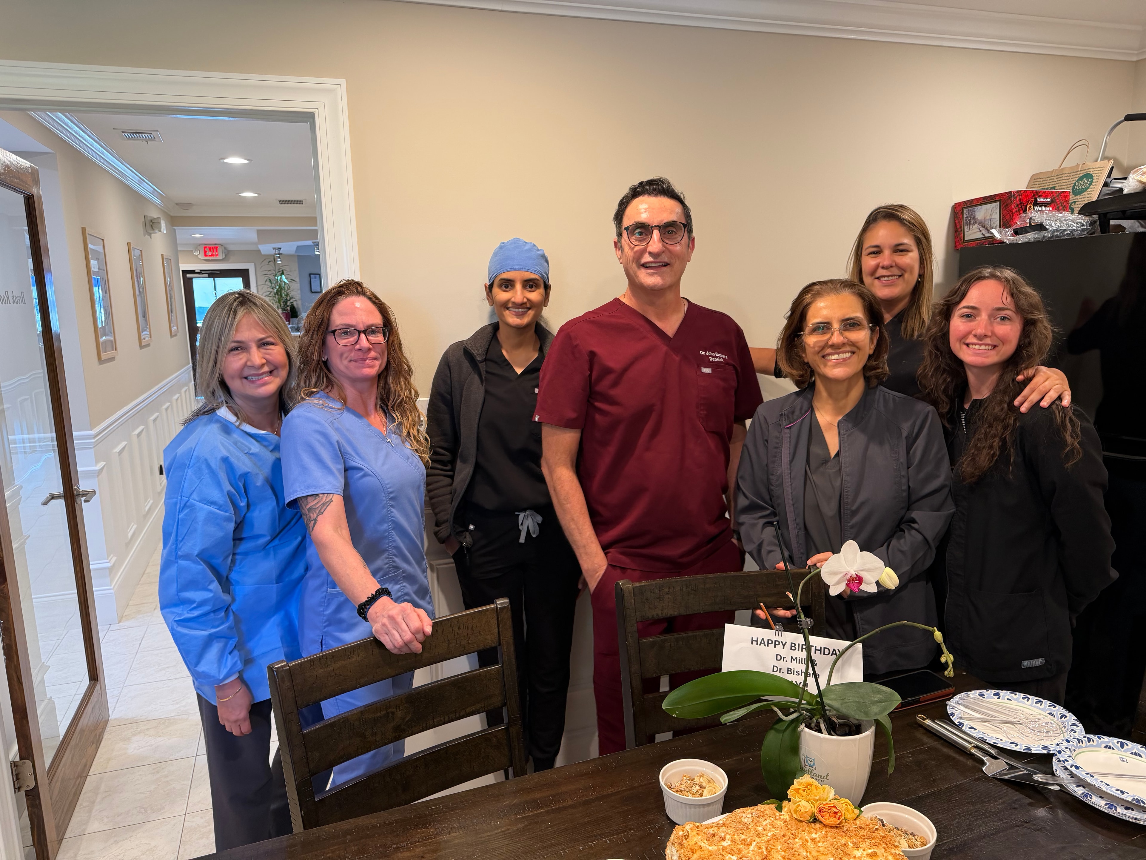 Merchants Walk Dental team gathered around a homemade birthday cake for Dr. Bishara and Dr. Patel