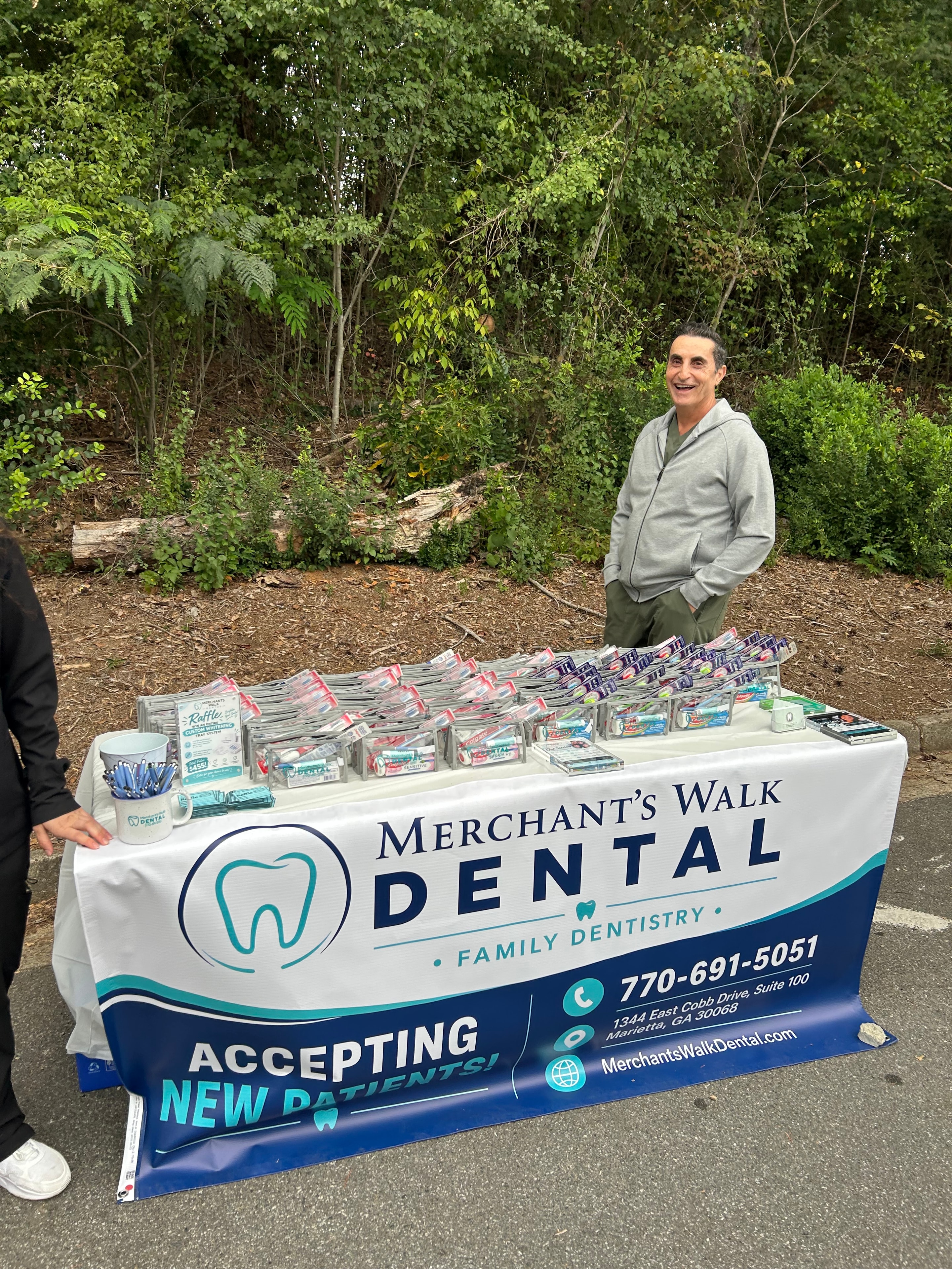 Dr. Bishara smiling behind the Merchants Walk Dental sponsor table at the Timber Ridge Fall Festival